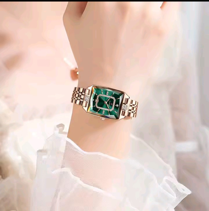 Luxury watch with green face and rose gold band on a wrist against a soft, blurred background