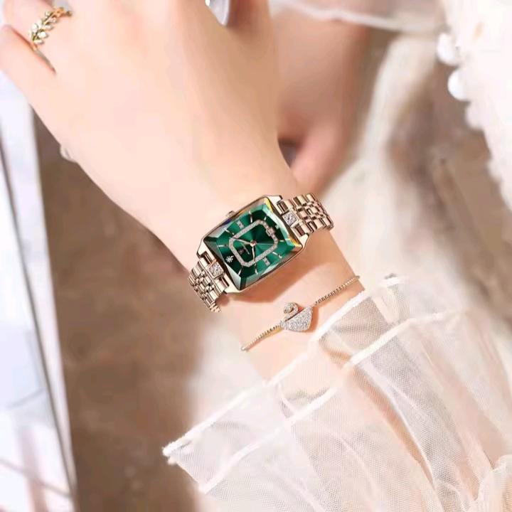 Close-up of a wrist wearing a green and gold watch with a blurred background
