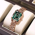 Luxury watch with rose gold strap and green face in a display case