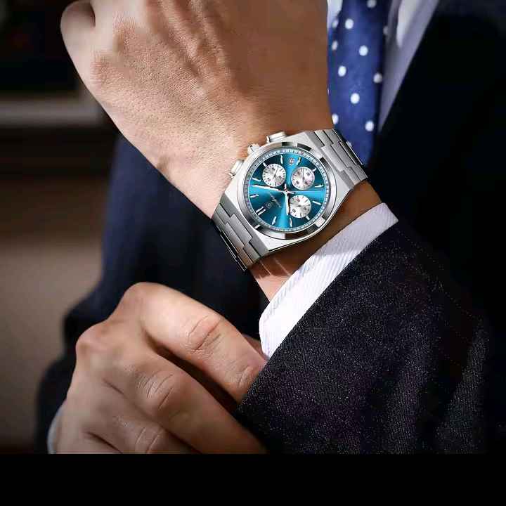 Close-up of a wrist wearing a watch with a blue face, set against a blurred background.